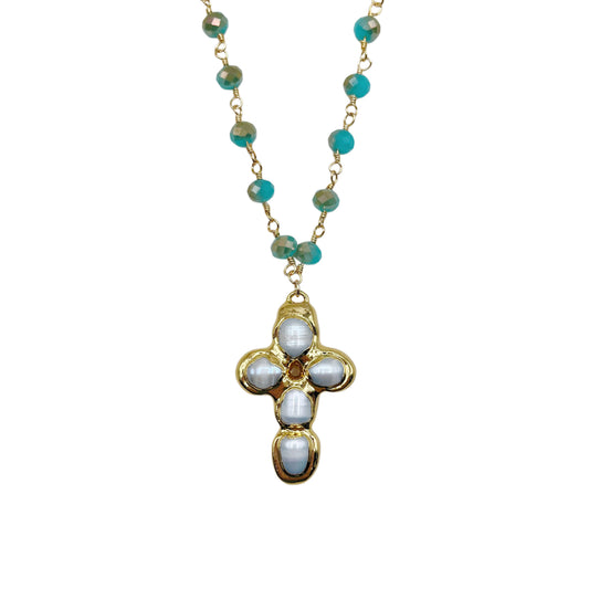 A gold chain necklace featuring turquoise-colored round beads and a central cross pendant adorned with white oval stones, set against a plain white background.