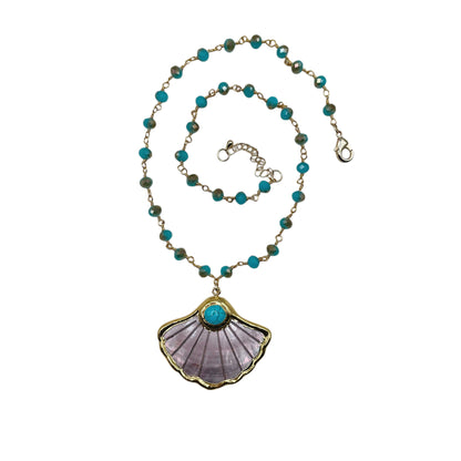 A beaded necklace with turquoise blue and olive green beads on a gold-tone chain, featuring a large scallop-shaped pendant with a purple inlay and a turquoise center stone.