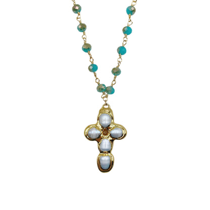 A gold chain necklace featuring turquoise-colored round beads and a central cross pendant adorned with white oval stones, set against a plain white background.