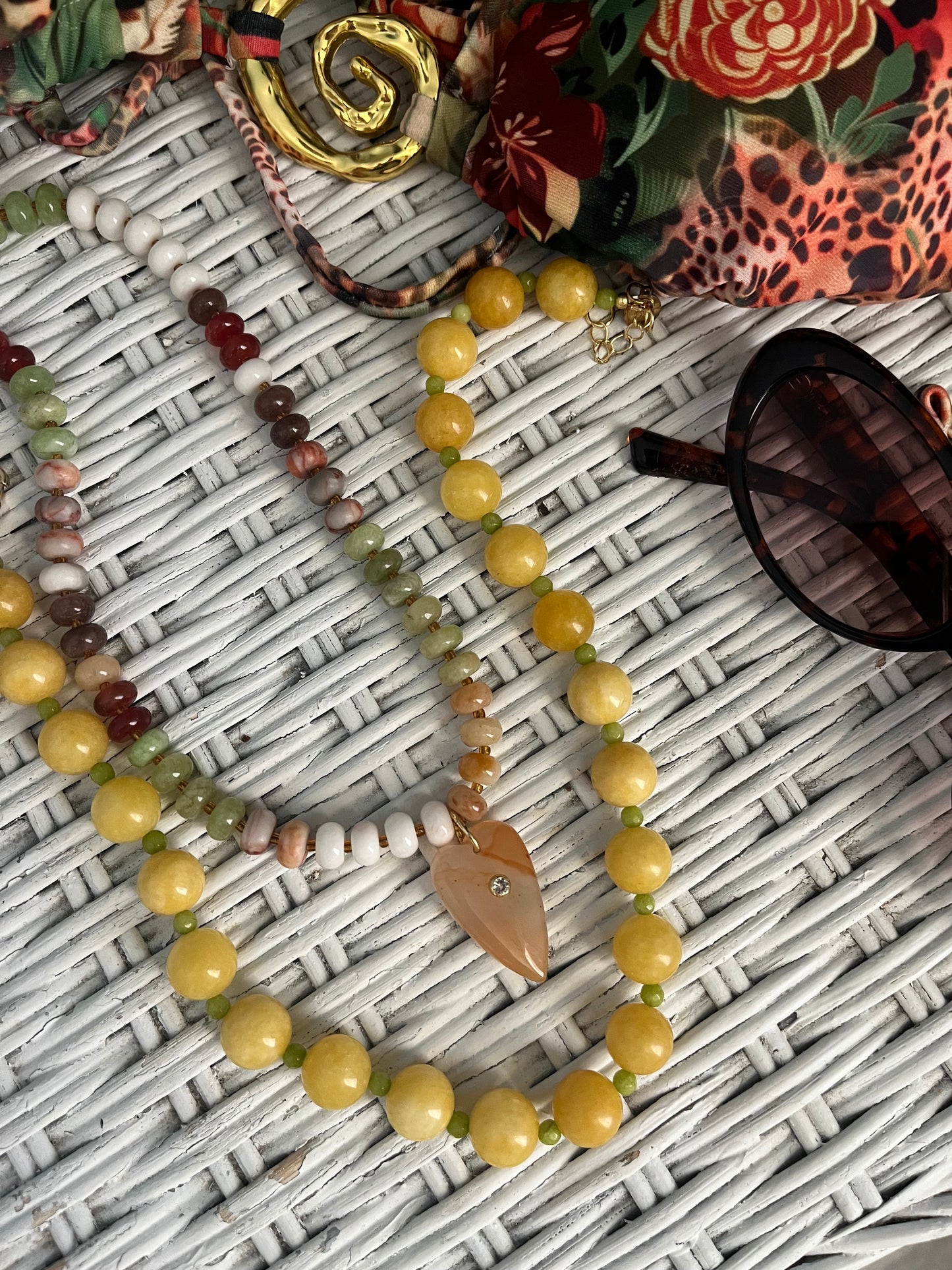 Two necklaces laying on a white wicker surface. 